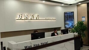 A reception desk at Wan Hao Hotel with a digital screen displaying room information. - Wanhao Business Hotel (New Barag Right Banner)