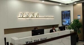 A reception desk at Wan Hao Hotel with a digital screen displaying room information.