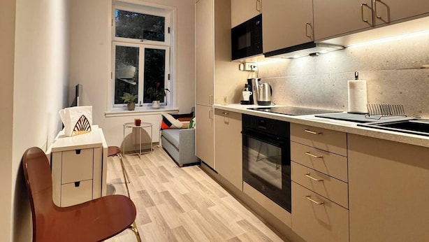 A modern kitchen with wooden flooring, built-in appliances, and a window providing natural light. - Stylish & Modern 2BR Apt, 4min Subway to Oslo City (Oslo)