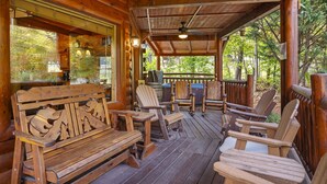 Une terrasse en bois avec un banc et des chaises, une table et un espace barbecue.