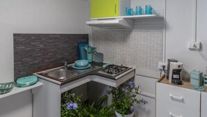 A compact kitchen with a gas stove, sink, and a bright green cabinet above. - Agricampeggio Princess - (3) (Fiorentina)