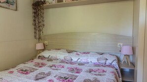Een slaapkamer met een bed voorzien van een bloemenquilt, twee bedlampen en een hangplant.