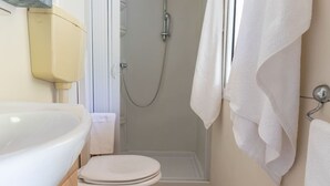 Een badkamer met een witte wastafel, toilet en douche.