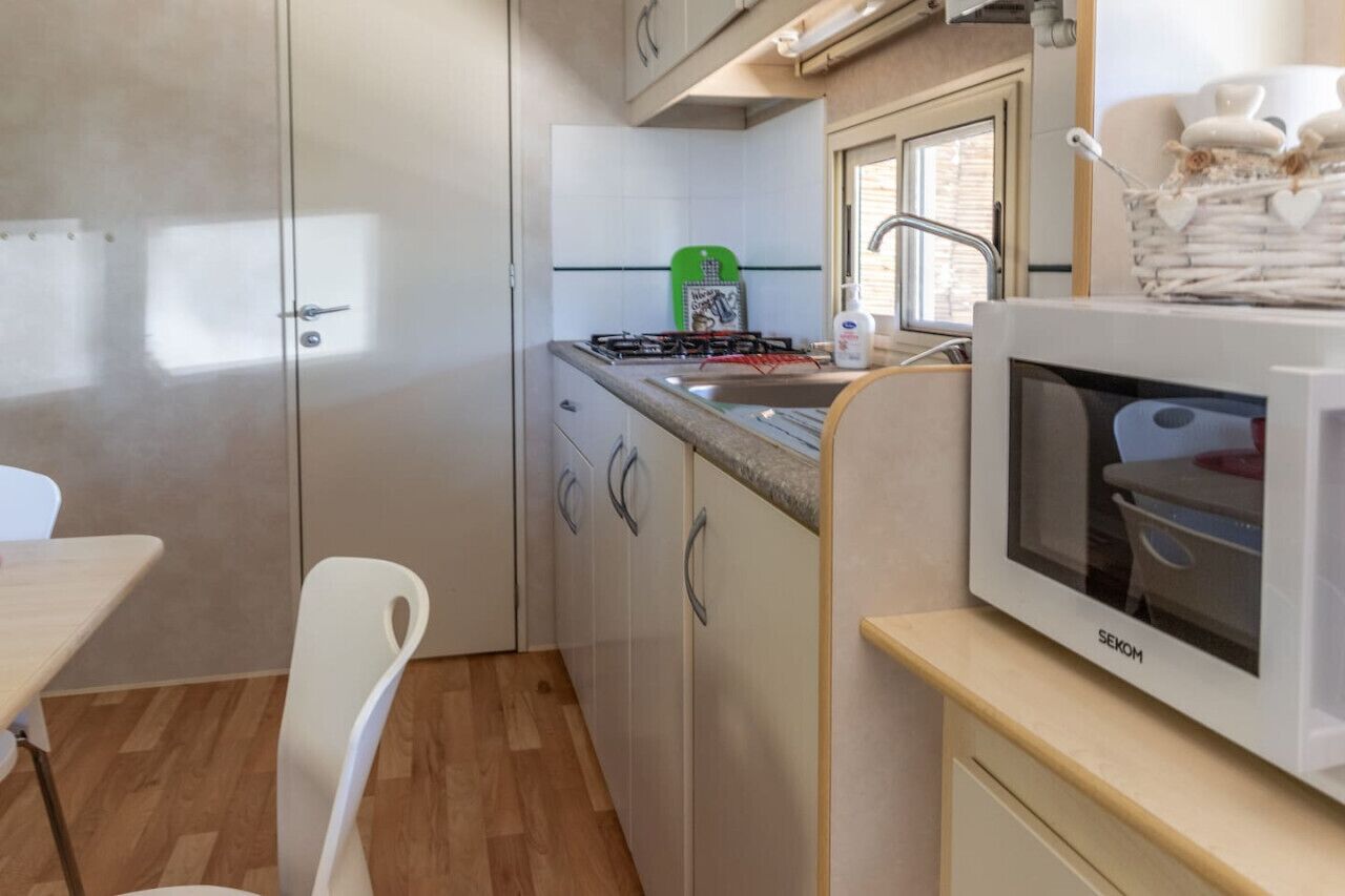 A compact kitchenette with a gas stove, a sink, and a microwave.