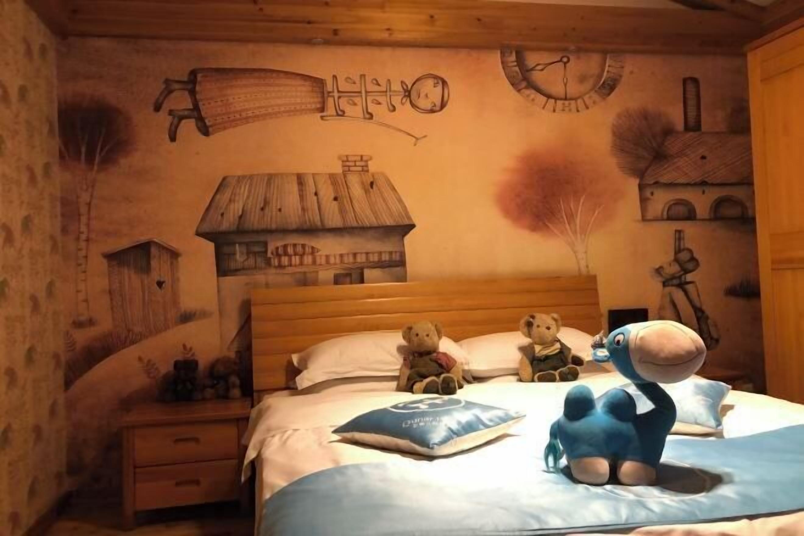 A bedroom with a wooden bed, pillows, a teddy bear, a blue plush toy, and a wall clock.