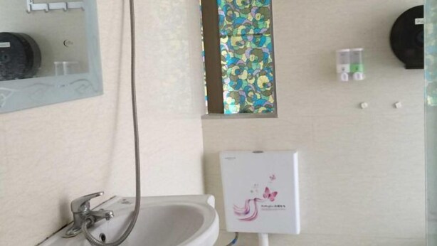A bathroom with a sink, a mirror, a shower, and a toilet. - Sinan Yulan Business Hotel (Sinan)