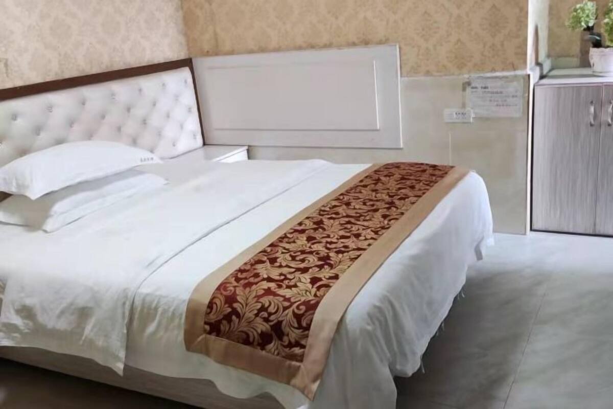 Een hotelkamer met een bed, hoofdeinde, kast en een muur met behang.