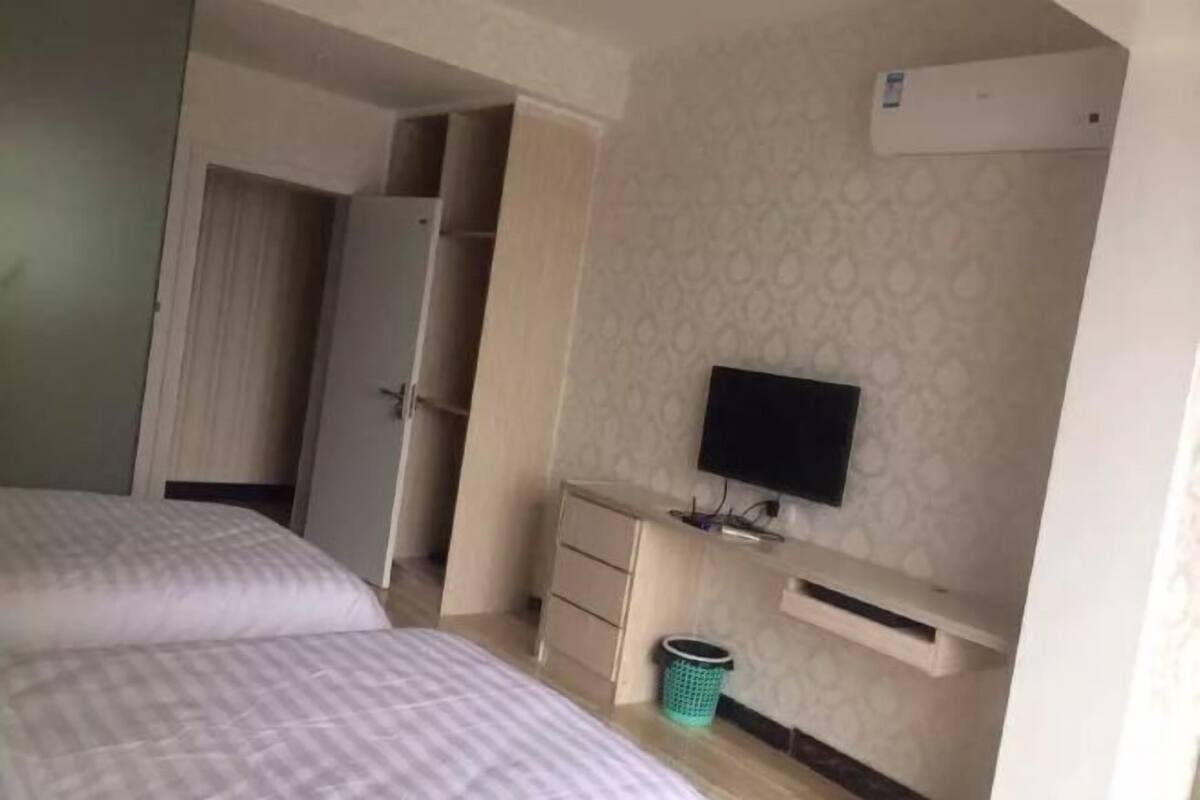 Een hotelkamer met een bed, een televisie, een kledingkast en een klein bureau.