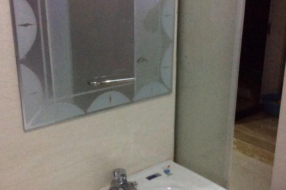 Une salle de bain avec un miroir, un lavabo et un petit objet décoratif posé sur le comptoir.