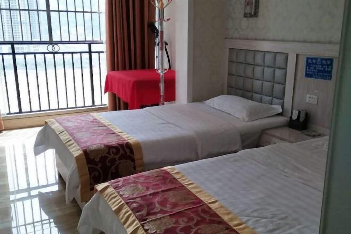 Een hotelkamer met twee bedden, een raam met uitzicht en een rode tafelkleed.