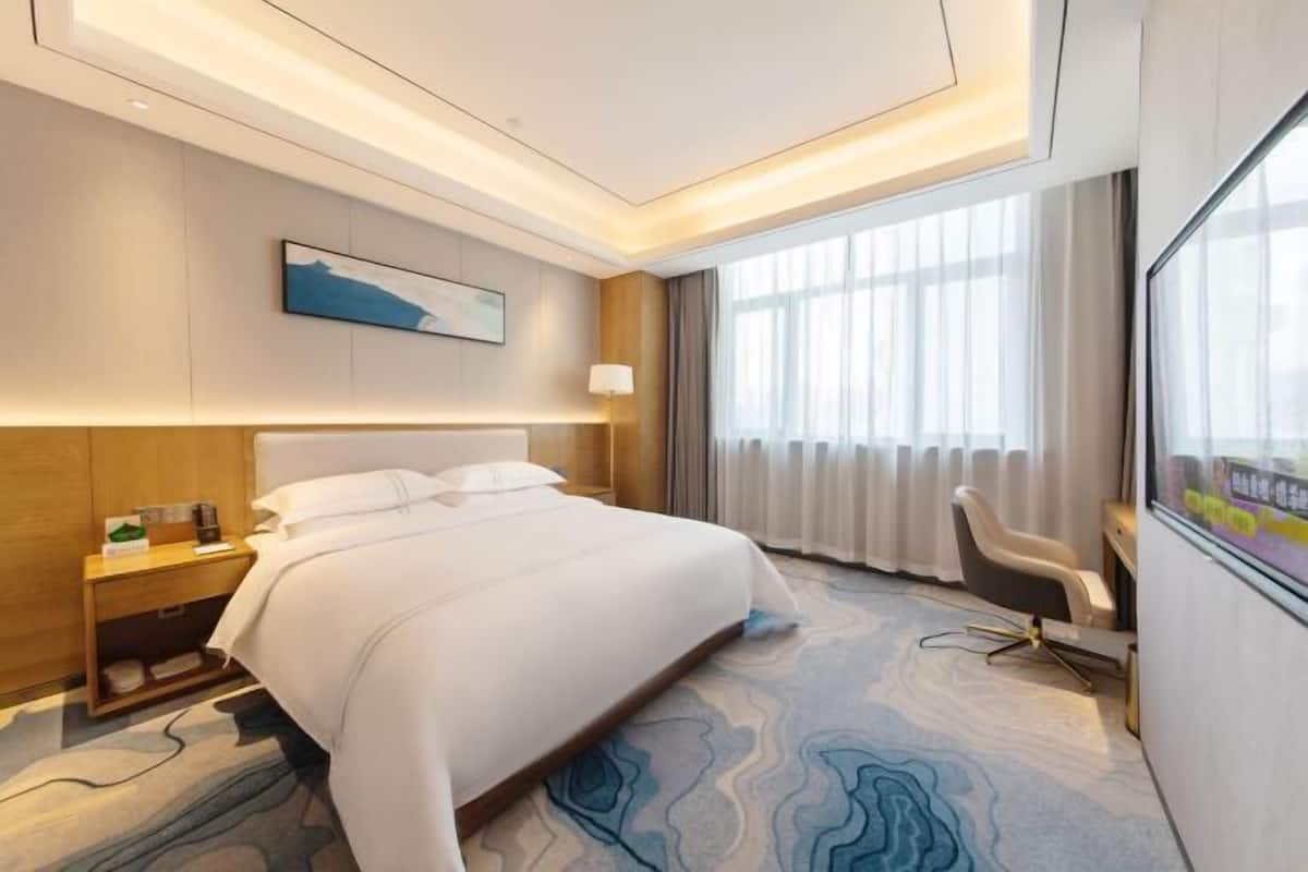 Une chambre d’hôtel moderne, dotée d’un grand lit, d’un bureau et d’une chaise.