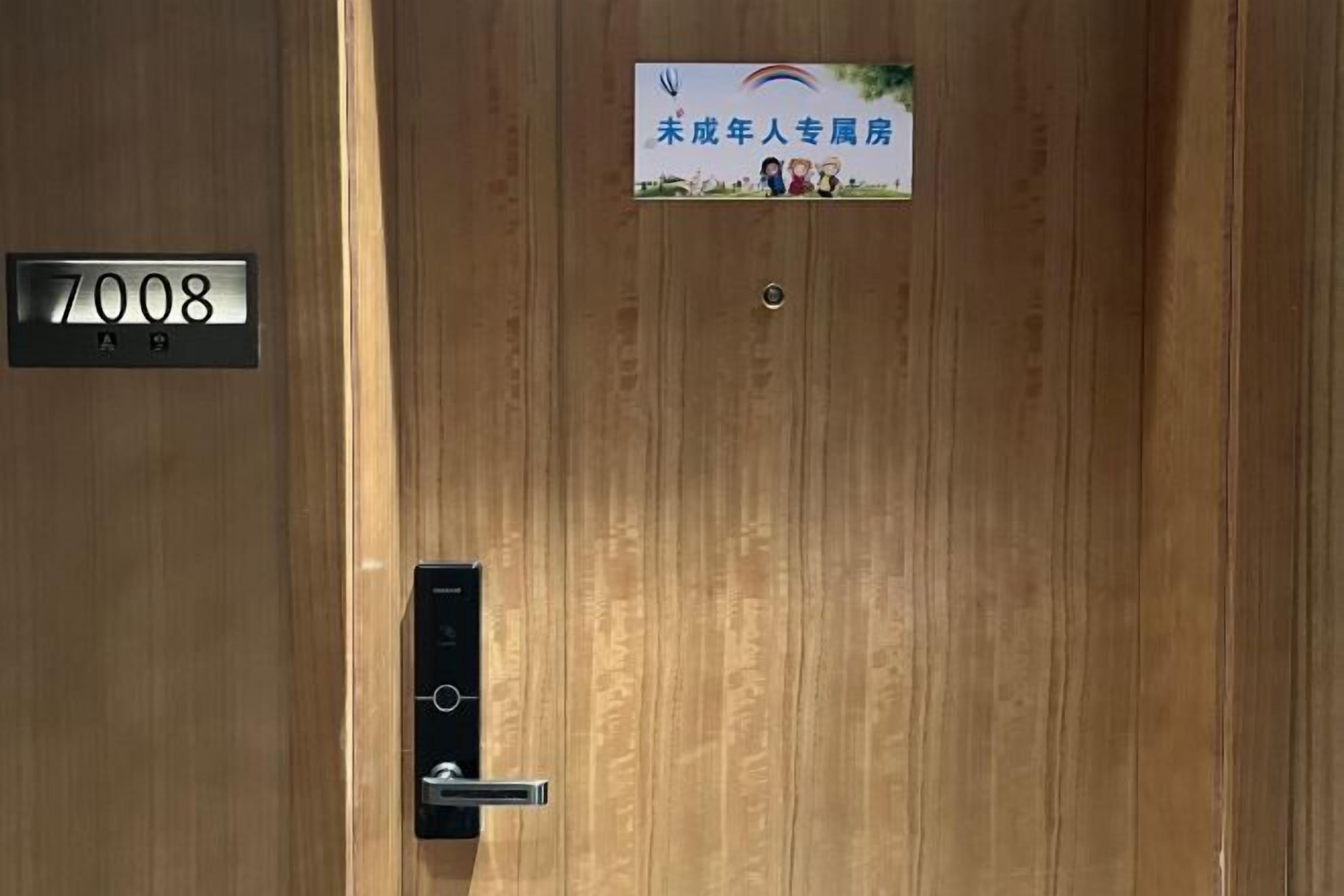 Una puerta de madera con una cerradura digital y un letrero que indica un albergue juvenil.