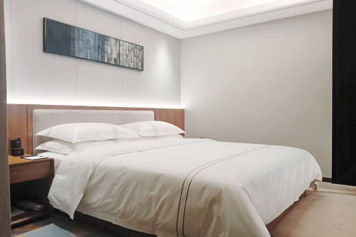 Une chambre d’hôtel avec un lit, une table de chevet et une œuvre d’art accrochée au mur.