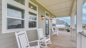 A covered porch with white rocking chairs and a wooden deck. - Walk to Sea Isle Beach! Canal-front Gem w/ Pool (Galveston)