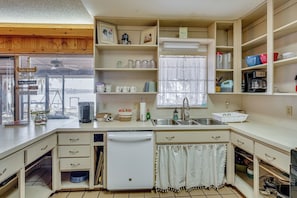 A compact kitchen with a dishwasher, sink, and various storage shelves. - Lake Winnott Home w/ Boat Ramp & Dock (Hawthorne)