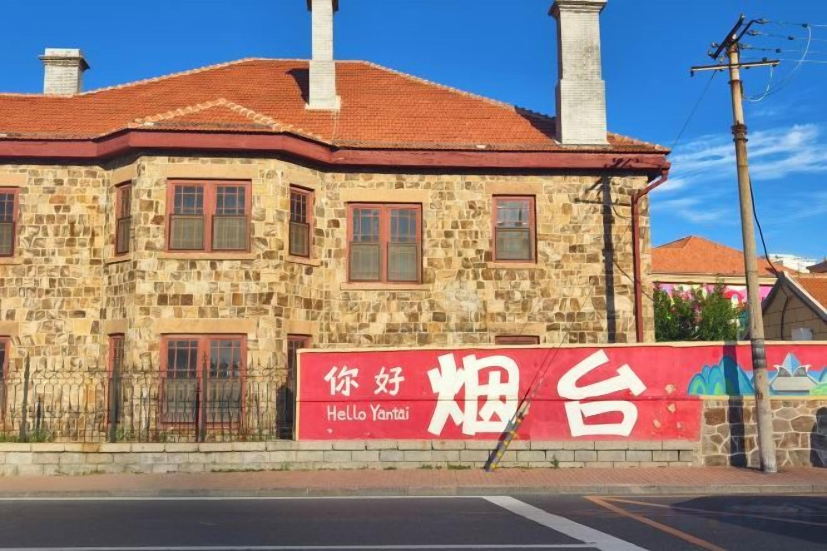 Un edifici de pedra amb un teulat vermell i un rètol que diu 'Hello Yantai'.