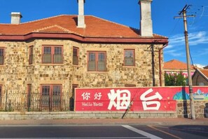 A stone building with a red roof and a sign that reads 'Hello Yantai.' - Zanzan Hotel (Yantai)