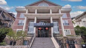 A hotel entrance with a grand facade, a staircase leading up to the doors, and a clear sky above.