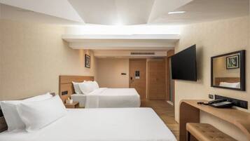 A hotel room with two beds, a desk, a TV, and a mirror.