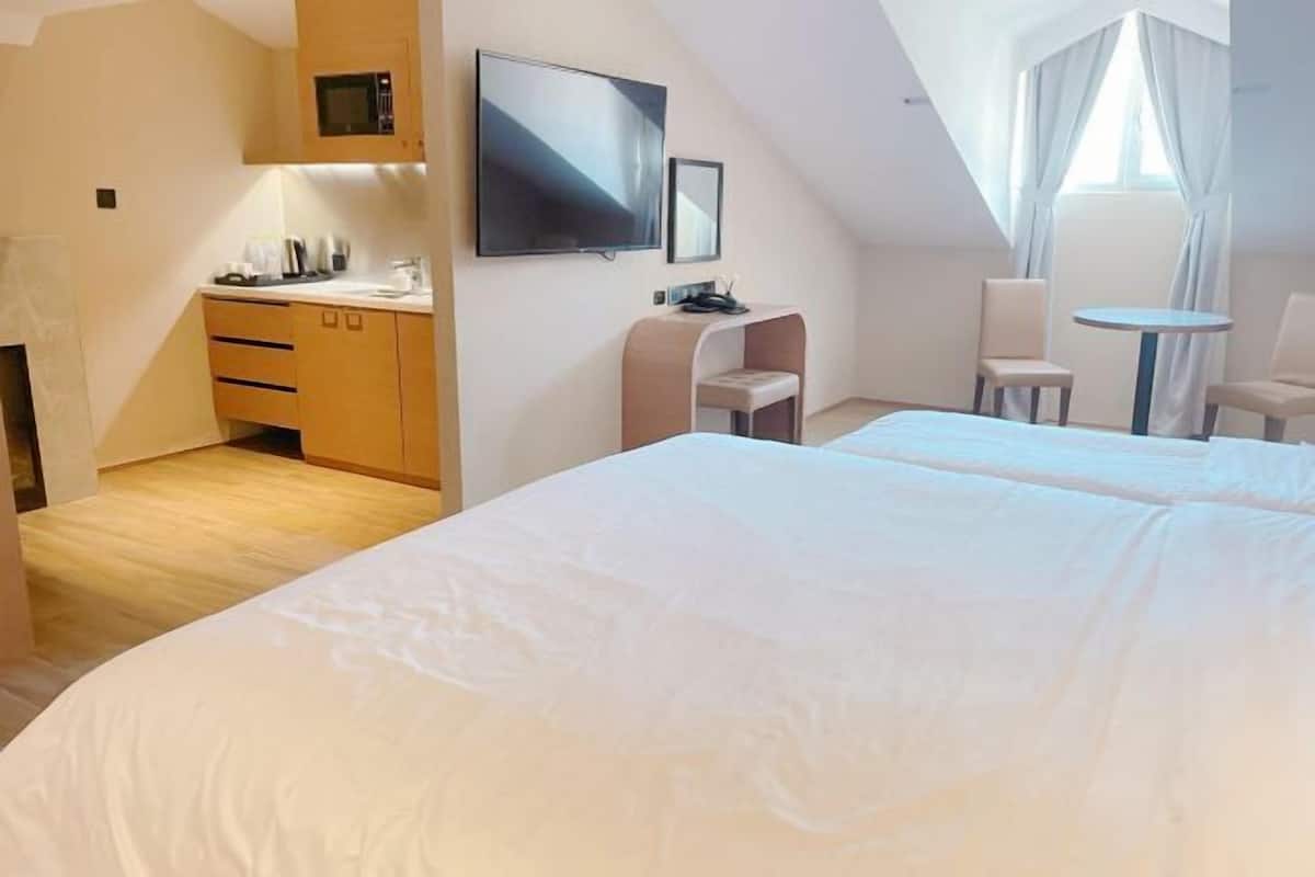 A hotel room with a bed, a TV, a desk, and a chair.