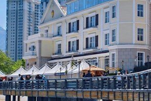 Un edificio de varios pisos con balcones, una zona de estar al aire libre cubierta y un puente de madera.