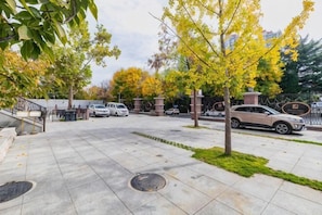 Ein Parkplatz mit Autos, einer Treppe und Bäumen mit gelben Blättern.