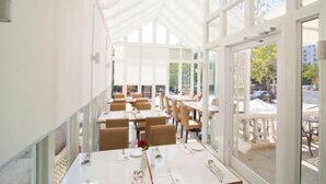 A restaurant with a high ceiling and large windows, offering a view of the outdoor area. - Zanzan Hotel (Yantai)