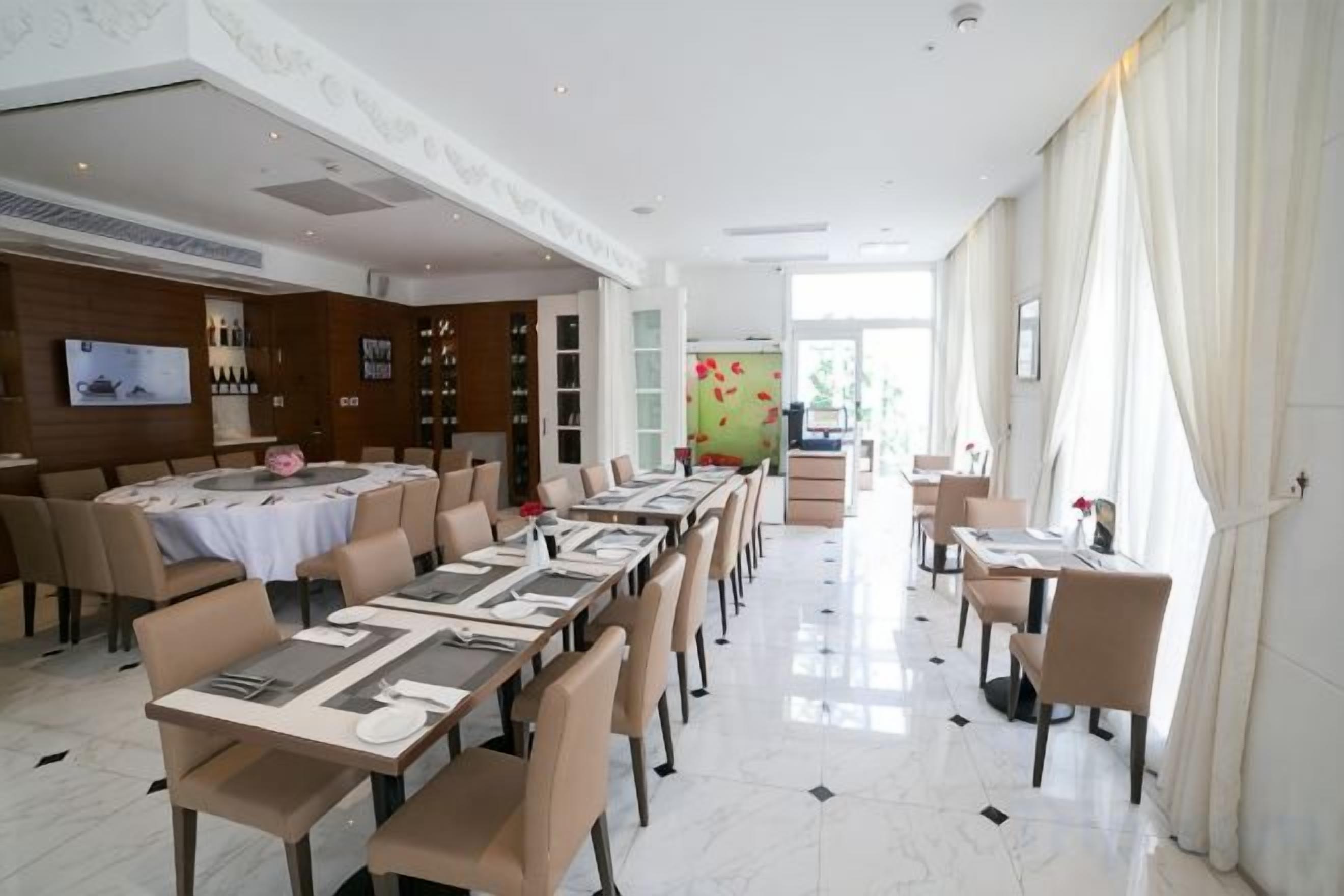 Un comedor de hotel con varias mesas y sillas, un televisor y una estantería para vinos.