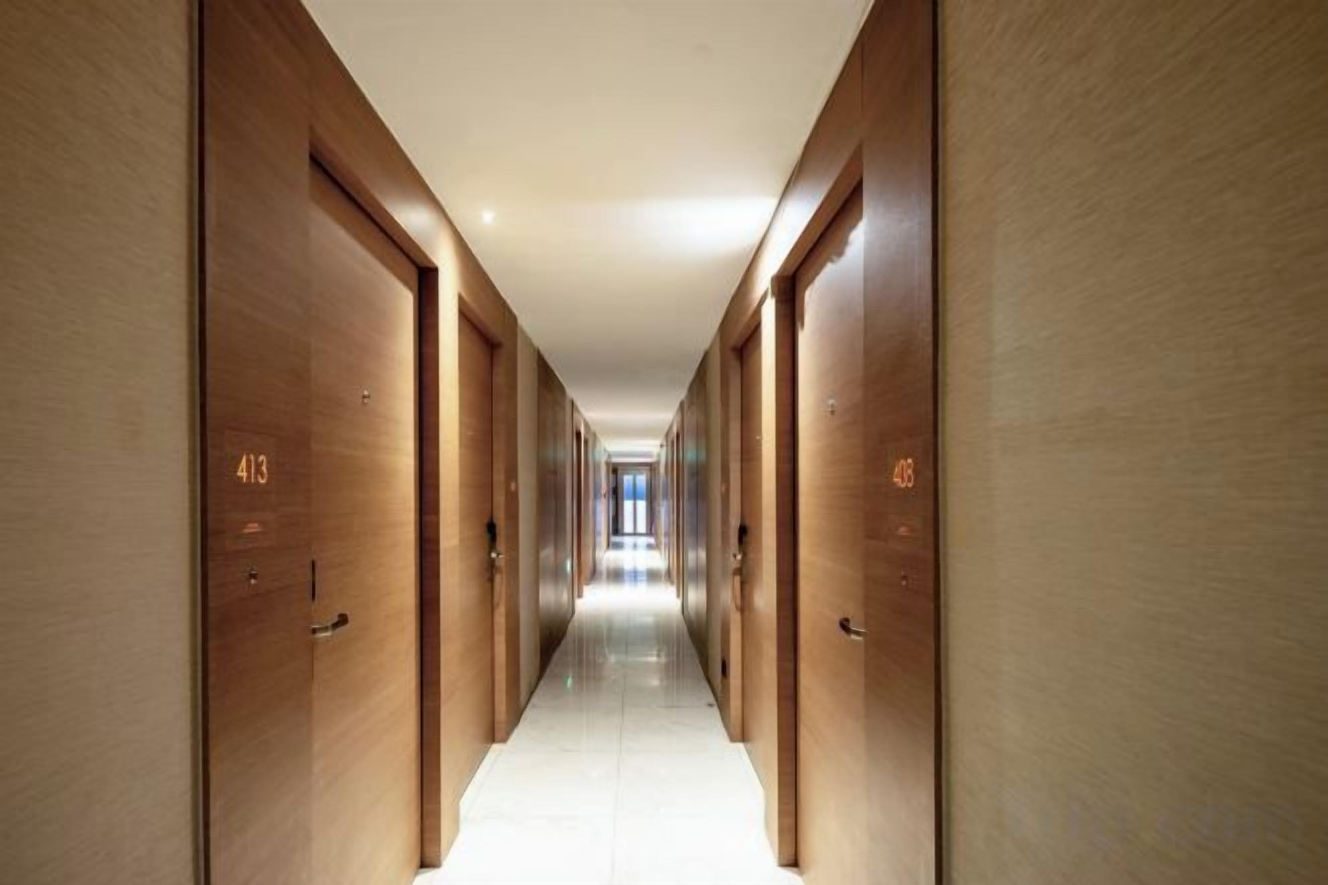 A long, narrow hallway with wooden doors, each marked with a number.