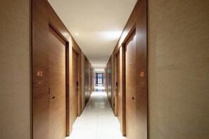 Un long couloir étroit, doté de portes en bois, chacune étant marquée d’un numéro.