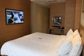 A hotel room with a bed, a television mounted on the wall, and a small desk with a telephone. - Zanzan Hotel (Yantai)