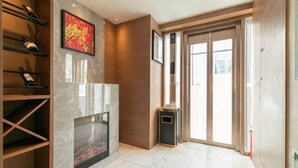 A modern interior with a fireplace, wooden shelving, and a large glass door leading outside. - Zanzan Hotel (Yantai)