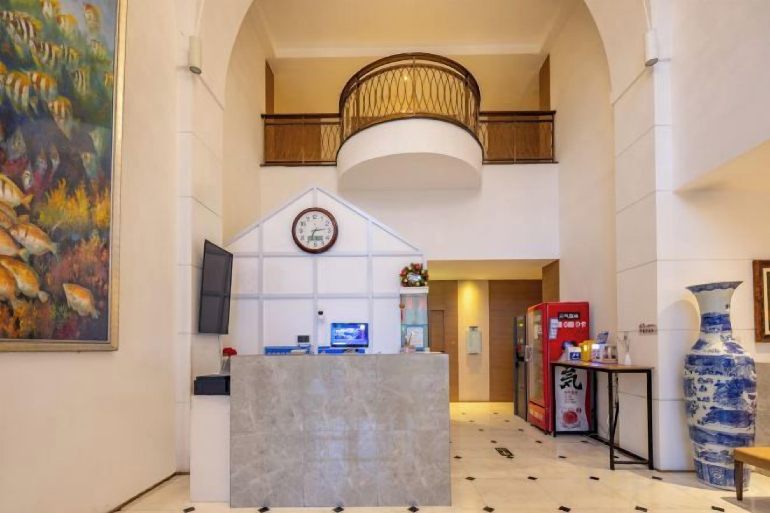 Rebedor d'hotel amb una recepció, un rellotge, un gerro gran i un quadre.