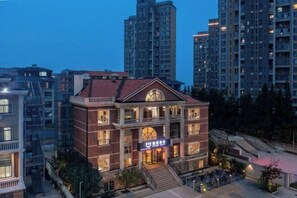 Un edificio de varios pisos con una entrada destacada y un balcón, rodeado de edificios residenciales altos.