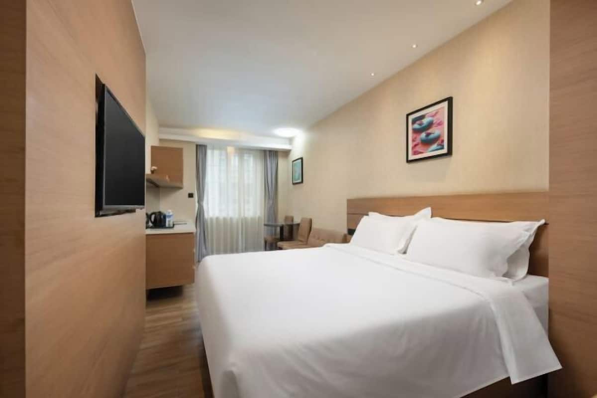 A hotel room with a bed, a TV, a desk, and a chair.