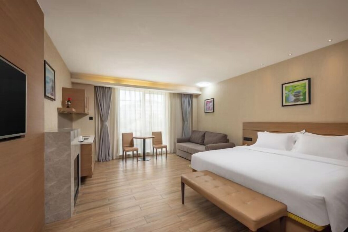 Una habitación de hotel con una cama, un escritorio, una silla, un sofá y un televisor.