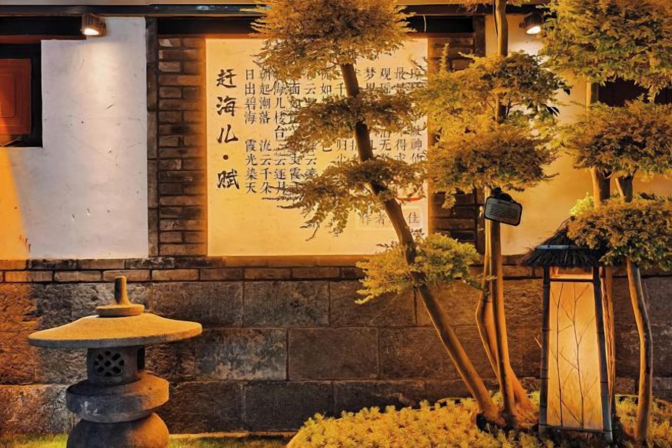 Un jardín japonés tradicional con un farol de piedra, un árbol bonsái y una pared con caligrafía.
