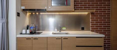A modern kitchen with a stainless steel microwave, wooden cabinets, and a brick wall.