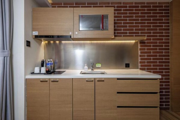 Eine moderne Küche mit Mikrowelle aus Edelstahl, Holzschränken und einer Ziegelwand.