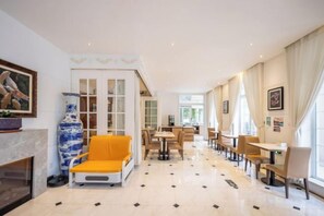 A hotel lobby with a fireplace, seating area, and dining space. - Zanzan Hotel (Yantai)