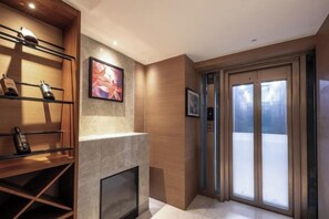 Un interior moderno con chimenea, estanterías de madera y un ventanal corredero que da a un balcón.