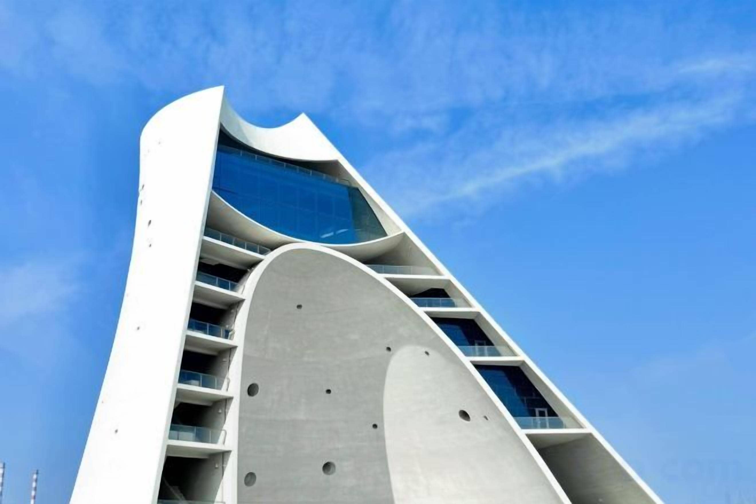 A modern building with a curved facade and multiple balconies.