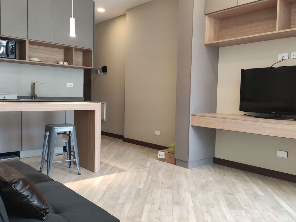 A modern kitchen with a built-in microwave, a wooden countertop, and a stool.