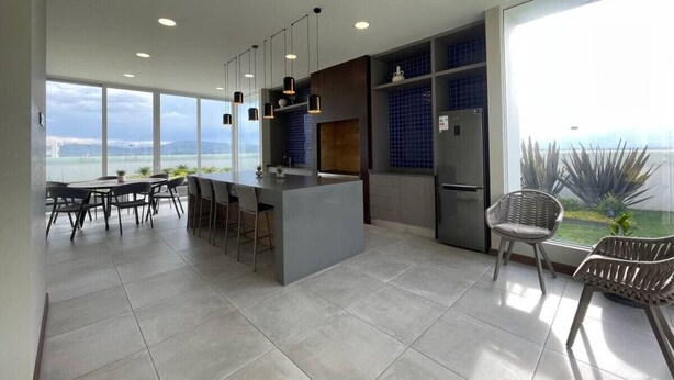 A modern kitchen with a central island, bar stools, and a view of the ocean. - Exclusive modern apartment with unbeatable location (Cochabamba)