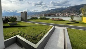 A landscaped terrace with a view of a town and mountains. - Exclusive modern apartment with unbeatable location (Cochabamba)