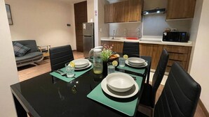 A dining area with a black table, four chairs, and a kitchen in the background. - Large and spacious apartment, well equipped and located (Cochabamba)