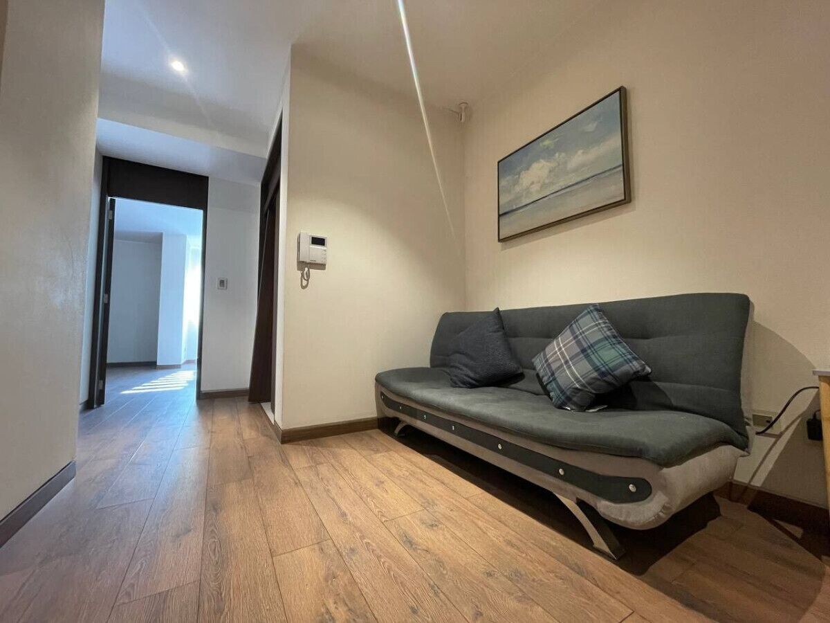 Ein modernes Wohnzimmer mit einer Couch, einem Bild an der Wand und einem Flur, der in einen anderen Raum führt.