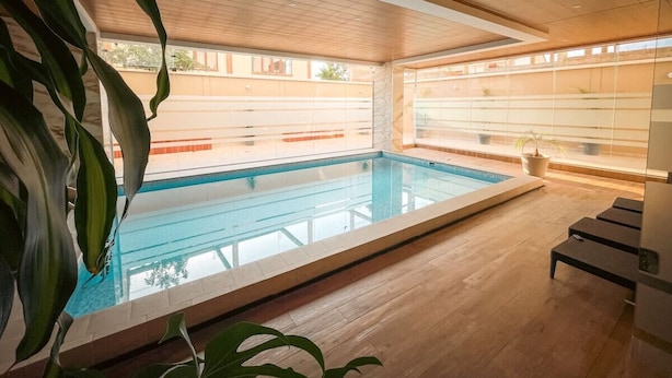 A modern indoor pool with a wooden floor and ceiling, large windows, and a view of the outside. - Large and spacious apartment, well equipped and located (Cochabamba)