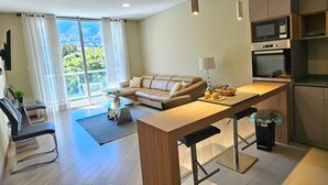 Een moderne woonkamer met een bank, een eethoek en een keuken met inbouwapparatuur.