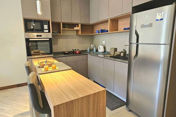 Una cocina moderna con electrodomésticos integrados, una mesa de comedor de madera y un refrigerador de acero inoxidable.